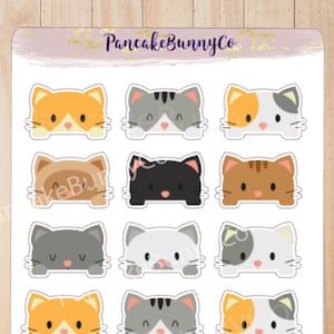 May include: A sheet of 18 cat face stickers. The stickers are white with a black outline and feature different colored cats with various expressions. The stickers are arranged in three rows of six. The text "PancakeBunnyCo" is at the top of the sheet.