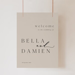 May include: A beige wedding welcome sign with black text that reads "welcome to the wedding of Bella and Damien 10 September 2022".