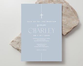 May include: A light blue baptism invitation card with white text. The card features a cross at the top and the name "CHARLEY" in a stylish font. The card includes the date, time, and location of the ceremony and lunch.