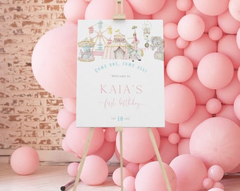 May include: A pink and blue welcome sign with a circus theme. The sign says "Come one, come all! Welcome to Kaia's first birthday. Sep 10, 2023".
