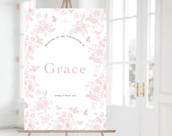 May include: A white welcome sign with a pink floral design and the text "Welcome to the Christening of Grace Sunday 21 March 2022".