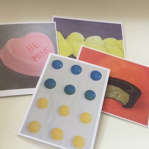 May include: Four cards with different illustrations. The first card has a pink heart-shaped candy with the words "Be Mine" on it. The second card has a row of yellow candies on a purple background. The third card has a pattern of blue and yellow candies. The fourth card has a brown candy on a red background.