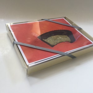May include: A set of greeting cards with a red background and a single image of a chocolate-covered peanut butter cup with a bite taken out of it.
