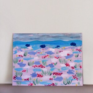 May include: A painting depicting a pink and blue landscape with a blue sky and white clouds. The landscape is covered in small pink, blue, and green flowers.