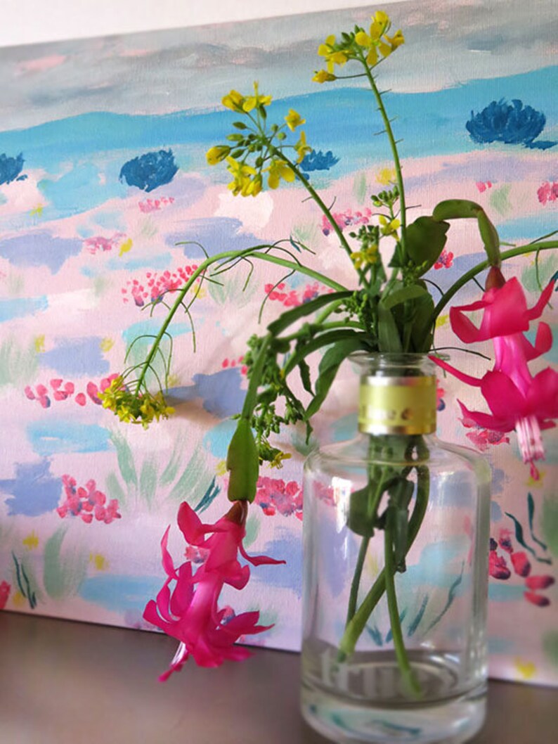May include: A clear glass vase with a yellow lid holds a bouquet of pink and yellow flowers against a painted background of pink, blue, and green.