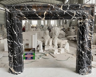 May include: A black and white marble fireplace mantel with gold accents. The mantel is in a warehouse setting with other marble pieces.