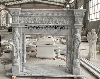 May include: A white marble fireplace mantel with ornate carvings and two sculpted figures on the sides. The fireplace is in a warehouse setting.