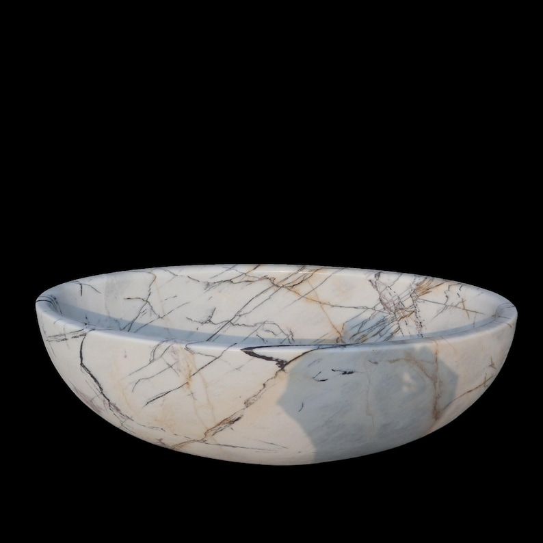 May include: Oval-shaped marble sink with a white base and intricate gray and brown veining. The sink has a smooth, polished surface and a shallow basin. The design is modern and elegant, suitable for a bathroom or powder room.