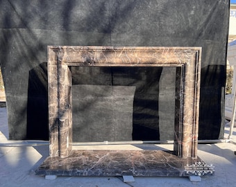 May include: A brown marble fireplace mantel with a rectangular opening. The mantel has a decorative border and a smooth, polished surface.