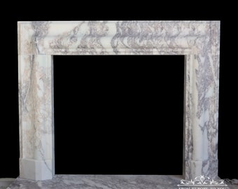 May include: A white marble fireplace mantel with a gray and white veined pattern. The mantel has a rectangular opening and a raised shelf. The mantel is made of natural stone and has a rustic, antique look.