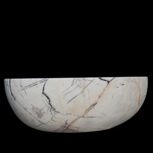 May include: A white marble bowl with a semi-circular shape. The bowl features dark gray and purple veining throughout the surface. The bowl is set against a black background.
