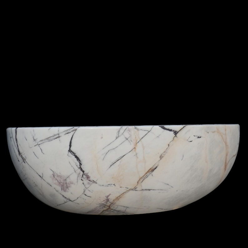 May include: A white marble bowl with a semi-circular shape. The bowl features dark gray and purple veining throughout the surface. The bowl is set against a black background.