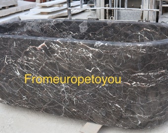 May include: A large, oval-shaped bathtub made of dark brown marble with white and grey veining. The bathtub is sitting on a concrete surface. The text "Frameuropetoyou" is visible on the side of the bathtub.