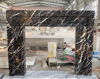 May include: Black and gold marble fireplace mantel with a white marble base. The mantel is in a warehouse setting.