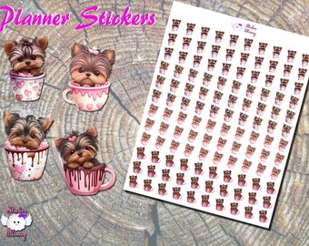 Op de afbeelding: Planner stickers met illustraties van Yorkshire Terriers in kopjes en mokken. De stickers zijn in aquarel stijl, met roze en bruine tinten. De vellen bevatten individuele stickers en een vel met meerdere stickers. De achtergrond is een houten oppervlak.