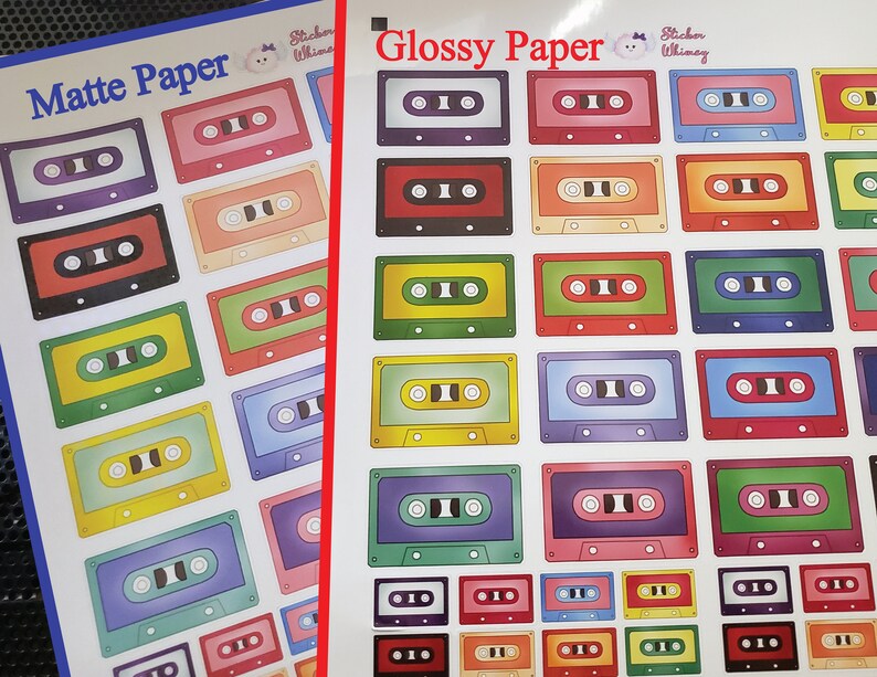 Op de afbeelding: Twee vellen papier met een verscheidenheid aan kleurrijke cassetteband-stickers. Het bovenste vel is gelabeld "Mat papier" en het onderste vel is gelabeld "Glanspapier".