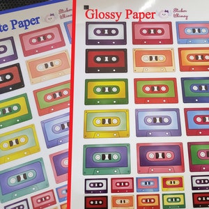 May include: Two sheets of paper with a variety of colourful cassette tape stickers. The top sheet is labelled "Matte Paper" and the bottom sheet is labelled "Glossy Paper".