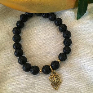 May include: Black lava rock beaded bracelet with a gold leaf charm.