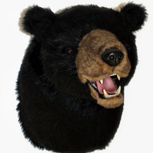 May include: A plush black bear head with a brown snout and open mouth, revealing white teeth and a pink tongue. The bear's fur is a deep black, and the ears have a lighter brown color.