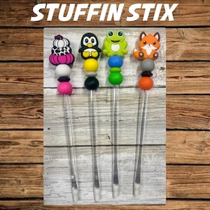 May include: Four clear plastic stix with colorful beads and cute animal toppers. The toppers include a pumpkin, penguin, frog, and fox.