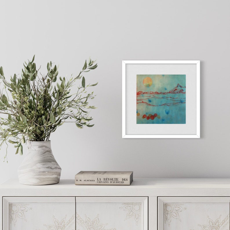May include: A framed abstract painting with a blue, green, and orange color scheme. The painting depicts a landscape with a sun, mountains, and water.