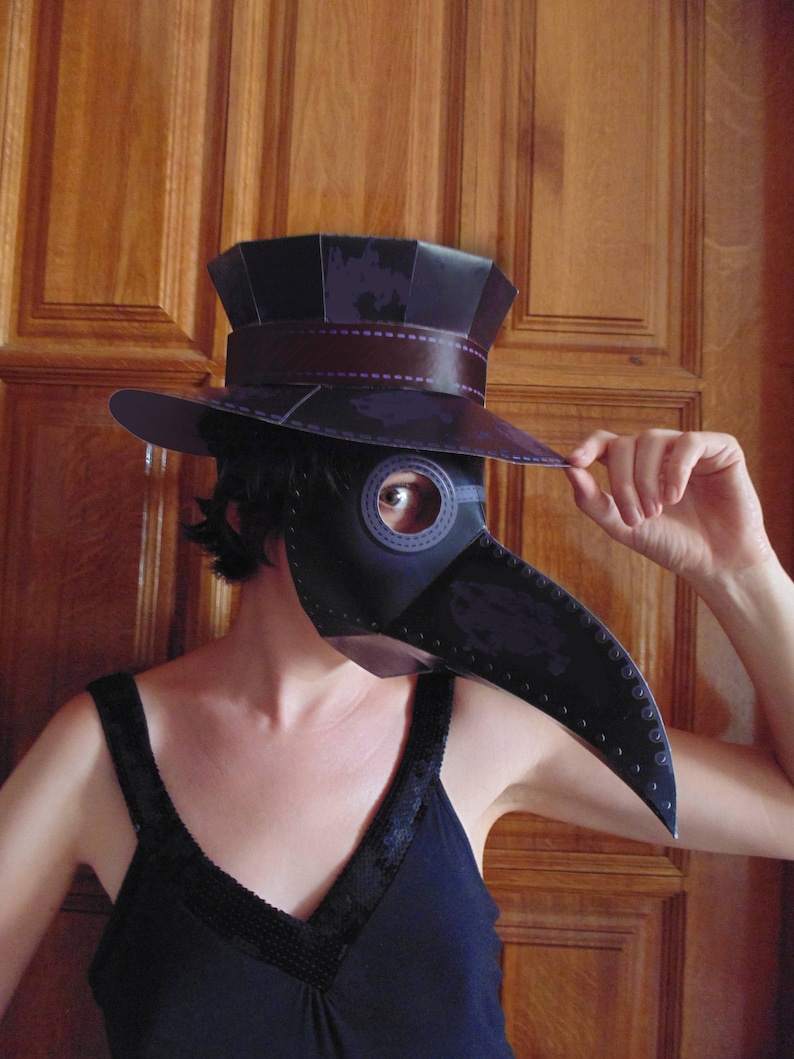 May include: A person wearing a black dress and a black and purple plague doctor mask with a tall black hat. The mask has a long, curved beak and a single eye hole.