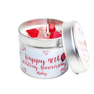 Puede incluir: Una vela blanca en una lata plateada con un diseño de rubí rojo. La vela tiene el texto "Happy 40th Wedding Anniversary Ruby" en la etiqueta.