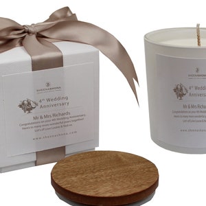 Peut inclure: Une bougie blanche dans un pot en verre avec un couvercle en bois. La bougie est décorée d'une étiquette qui dit "4th Wedding Anniversary" et "Mr & Mrs Richards". La bougie est emballée dans une boîte blanche avec un ruban en satin marron.