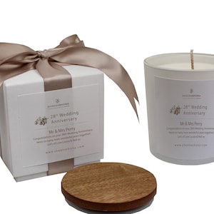 May include: A white gift box with a brown satin ribbon tied in a bow. The box has a label that says "28th Wedding Anniversary" and "Mr & Mrs Perry". The box is next to a white candle with a wooden lid. The candle has a label that says "28th Wedding Anniversary" and "Mr & Mrs Perry".