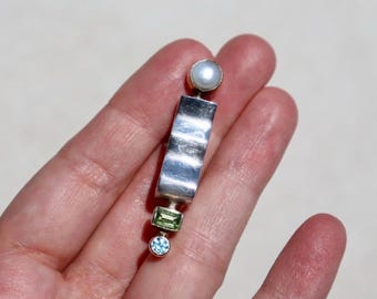 Broche em prata de lei com design geométrico, peça marcante para lapela, feito à mão com pérola, topázio e peridoto, em estilo pós-moderno.