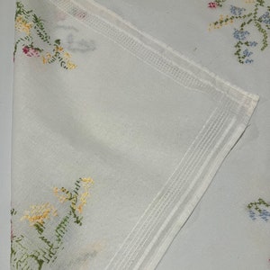 Pu&ograve; includere: Tovaglia bianca con ricami floreali in tonalit&agrave; rosa, giallo, verde e blu.