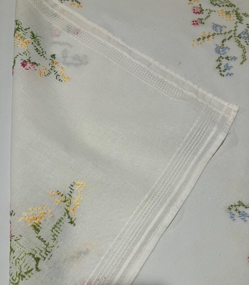 Pu&ograve; includere: Tovaglia bianca con ricami floreali in tonalit&agrave; rosa, giallo, verde e blu.