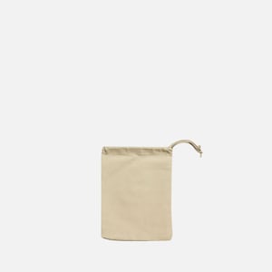 May include: A plain, off-white drawstring bag made of cotton fabric. The bag is empty and has a single drawstring.