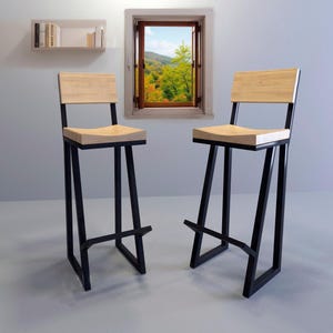 May include: Two black metal bar stools with wooden seats. The stools have a unique angled design and are perfect for a modern kitchen or dining area.