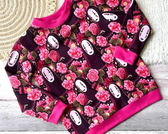 Może przedstawiać: Bluza z długim rękawem z powtarzającym się wzorem postaci z Spirited Away i różowych róż na ciemnobordowym tle. Mankiety i dekolt są w kolorze jasnoróżowym.