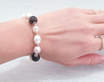 May include: A bracelet with white, pink, and black beads. The beads are accented with small silver rhinestones.