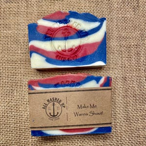 May include: Two bars of handmade soap with red, white, and blue swirls. The top bar has an anchor emblem. The bottom bar has a brown paper label that reads "All Washed Up Soap Shop" and "Make Me Wanna Shout!"