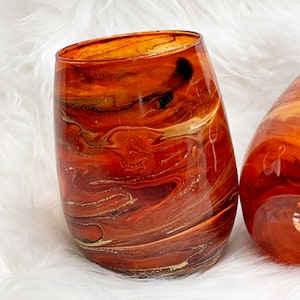 May include: A clear glass vase with a swirling orange, brown, and gold pattern. The vase is perfect for displaying flowers or other decorative items.
