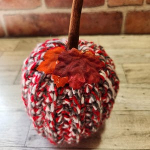 Puede incluir: Decoración de calabaza hecha a mano, tejida en rojo, blanco y gris. Cuenta con un tallo de canela y hojas decorativas. Un artículo de temporada ideal para la decoración otoñal.