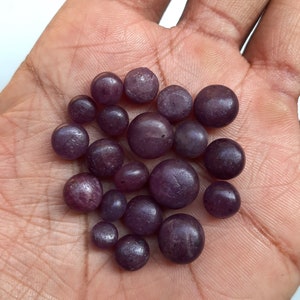 Può includere: Una collezione di piccole pietre preziose rotonde e viola. Le pietre sono lisce e hanno una leggera lucentezza.