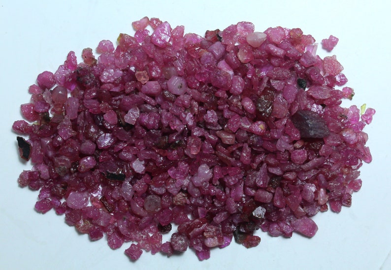 K&ouml;nnte beinhalten: Ein Haufen roher, ungeschliffener Rubin-Edelsteine. Die Rubine variieren in Gr&ouml;&szlig;e und Form und zeigen eine Reihe von rosa und tiefroten Farbt&ouml;nen. Die rohen Edelsteine haben ein nat&uuml;rliches, unpoliertes Aussehen mit sichtbaren Texturen und Facetten.