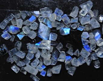 May include: A collection of iridescent moonstone chips in various sizes and shapes. The chips are translucent and have a blue sheen.