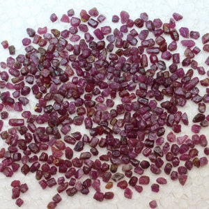 May include: A large collection of small, rough, red ruby gemstones. The rubies are various shapes and sizes, and have a natural, unpolished look.