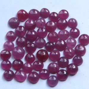 Peut inclure: Un ensemble de pierres précieuses rubis polies et rondes, de nuances de rouge et de rose. Les pierres sont dispersées sur une surface claire, mettant en valeur leurs surfaces lisses et réfléchissantes. Les gemmes sont de tailles variées.
