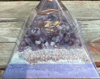 May include: A clear pyramid with a copper wire spiral inside. The pyramid is filled with amethyst crystals and copper flakes. The base of the pyramid is a solid purple color.