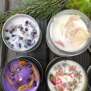 Pu&ograve; includere: Quattro candele in barattoli di metallo con diverse decorazioni di fiori e erbe secche. Le candele sono di colore bianco, viola e beige chiaro.