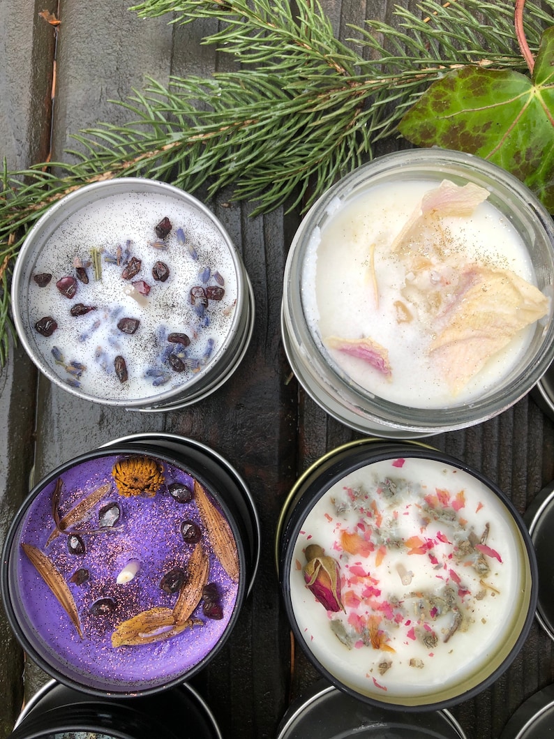 Pu&ograve; includere: Quattro candele in barattoli di metallo con diverse decorazioni di fiori e erbe secche. Le candele sono di colore bianco, viola e beige chiaro.