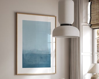 May include: A dining room with a white table with a white and gold inlay, four woven cane chairs, a white ceramic teapot, and a white pendant light with a textured white shade hanging over the table. A framed abstract painting with blue and white colors hangs on the wall behind the table. The text "Inspiration Abstracts" is printed below the painting.