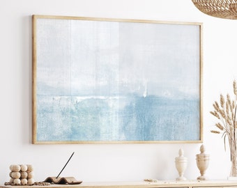 May include: A framed abstract art print with a light blue and white color palette. The artwork has a textured appearance and is encased in a natural wood frame. The print is displayed above a wooden cabinet, creating a serene and minimalist aesthetic.