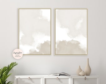 May include: Two beige abstract watercolor paintings with a gold frame, hanging on a white wall above a white cabinet with two doors.